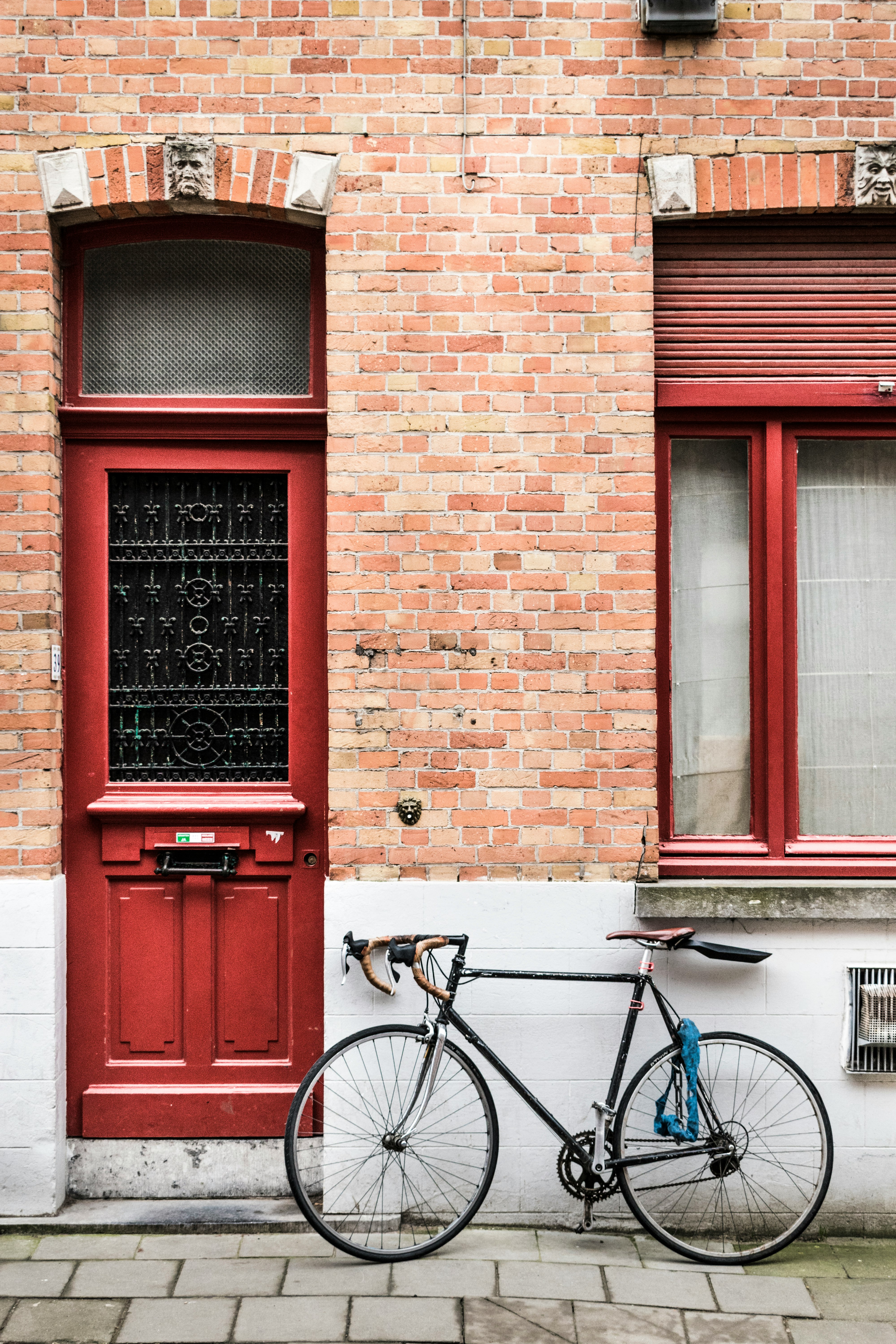 blue city bike parked beside red wooden door